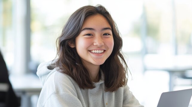 Smiling teenage girl studying with laptop in modern classroom, focused student in university learning, education success, youthful enthusiasm and technology.