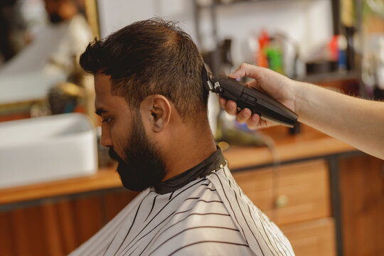 A skilled barber cutting hair in a stylish salon, highlighting modern grooming techniques and artistry