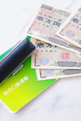 テーブルの上に置かれた銀行の預金通帳と印鑑、1万円札
