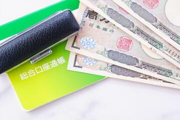 テーブルの上に置かれた銀行の預金通帳と印鑑、1万円札
