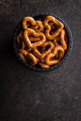Heart shaped pretzel in bowl on black table. Top view.
