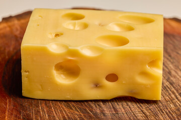 a piece of emmental cheese on a wooden chopping board