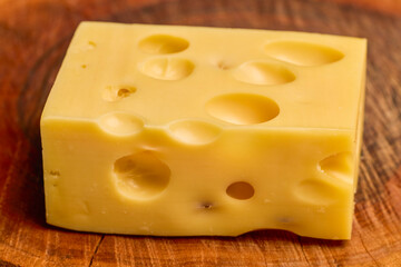 a piece of emmental cheese on a wooden chopping board