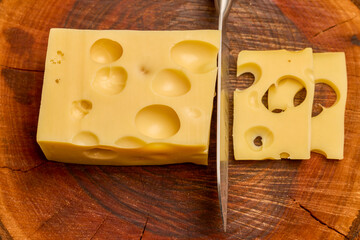 a piece of emmental cheese on a wooden chopping board
