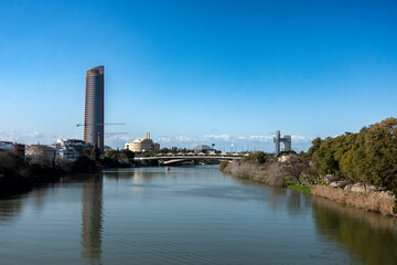 Obraz premium View of the Guadalquivir River and in the background the Torre Sevilla, completed in 2015, which is reflected in it. Seville, Andalusia, Spain.