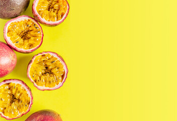 Top view of group of whole and cut in halves ripe raw passion fruit or maracuya with sweet edible juicy pulpy seeds on bright yellow background with copy space used as healthy sweet dessert snack