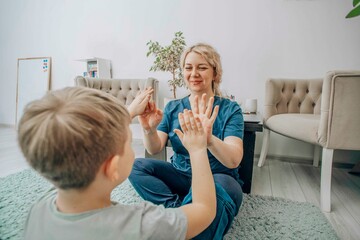 child and therapist learning sign language together on soft carpeted floor, natural light and...