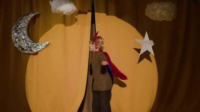Slow motion of Caucasian boy wearing prince costume appearing on theater stage, spinning round and running behind curtains