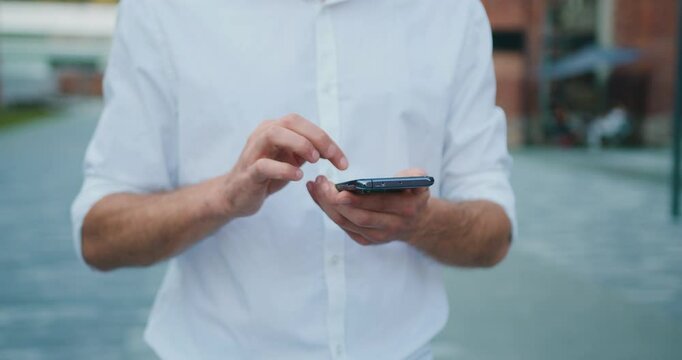 Mobile phone in male hands at outdoors Portrait of male hands holding smartphone typing text or shopping online, reading social media internet.