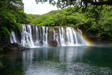 Fototapeta premium Rainbow forming over a majestic waterfall, mist rising from the powerful currents below, creating a magical nature spectacle