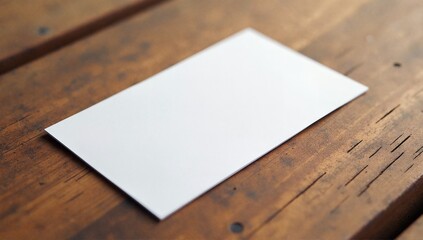 Fototapeta premium A pristine blank business card placed on a rustic wooden table, ideal for showcasing branding or personal information in a customizable format.