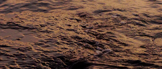 Close up shot of wave splashing with sunset light reflection