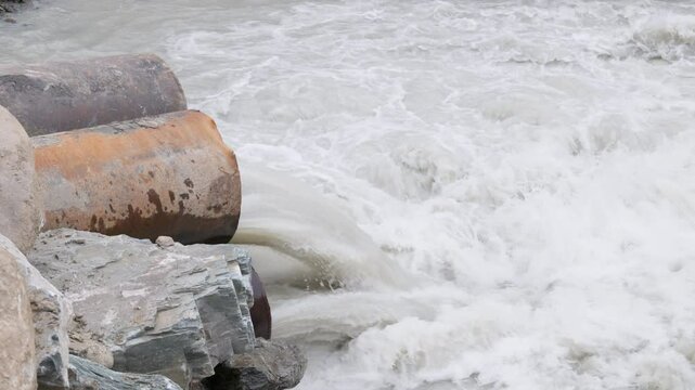 mountain river water flowing through temporary pipe bridge across the mountain river using steel pipes and a soil embankment