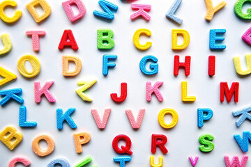 Colorful foam alphabet letters scattered on white background.