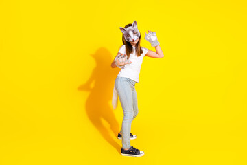 Young girl in playful cat mask and paws posing against a bright yellow background in casual attire