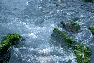 In overcast weather, waves hit the rocks at the seaside