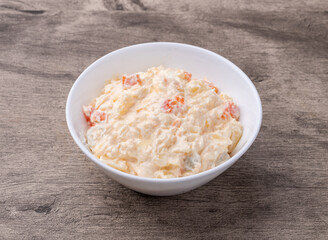 Russian salad or mayonnaise salad in a bowl over wooden table