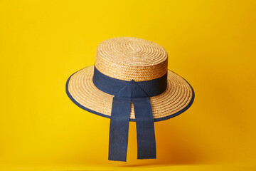 Straw high hat with blue ribbons isolated on the bright solid fond plain yellow background