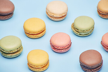 Fresh small various color macaron biscuit cookies pattern isolated on the bright solid fond plain bright blue background