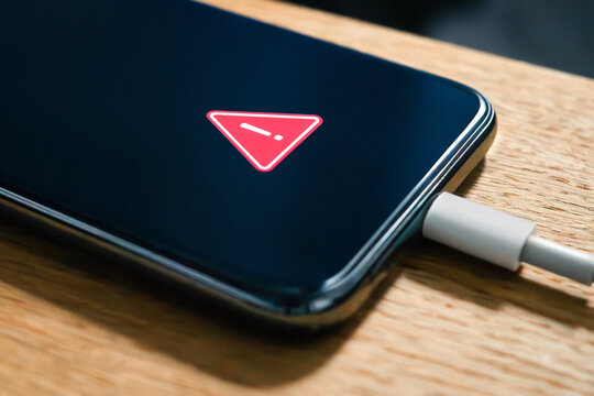 Phone battery charge error and problem. Charger usb cable issue. Overheating or low performance recharge in smartphone. Hot lithium mobile damage safety warning. Cellphone crash. Wood table.