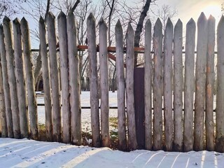 Old abandoned fence on a sunny winter day. Background texture of an old wooden fence
