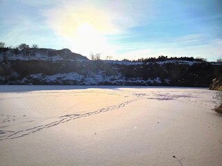 Beautiful winter landscape with sun glare. Frozen lake with footprints and skating tracks