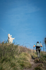Obraz premium Woman climbing Naranco Mountain in Oviedo, Spain, finds statue of Christ the Redeemer at the top.