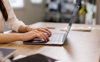 Hand of young asian female teacher or student typing on laptop keyboard while sitting by desk in...