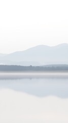 Tranquil lake with layered misty mountains fading into soft atmospheric distance