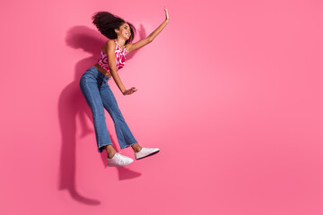Happy young woman posing with charm in a trendy outfit against a pink background, showcasing joyful energy and casual style