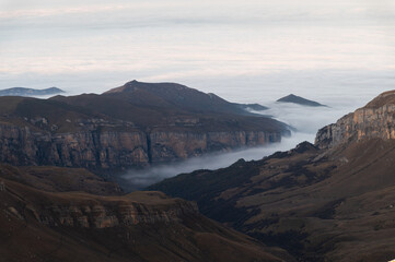 Beautiful sea of clouds in the morning in the mountains. Rocky mountains with cliffs covered with thick clouds after sunset