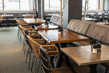  Modern cafe setting with a bustling and lively environment, a blurred view of chairs, tables, and people. Contemporary cafe design, highlighting the use of natural materials and comfortable seating.