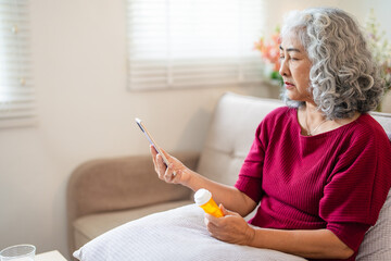 Health care concept, asian senior woman using smart phone reading, searching prescription on bottle...