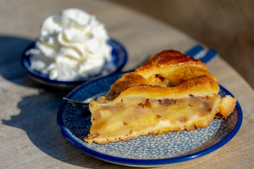 Selective focus of homemade apple pie in the plate served with whipping cream on the side, A pie in which the principal filling ingredient is apples, The earliest printed recipe is from England.
