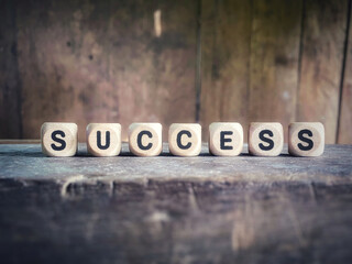 Success word on wooden cubes with retro background. Stock photo.