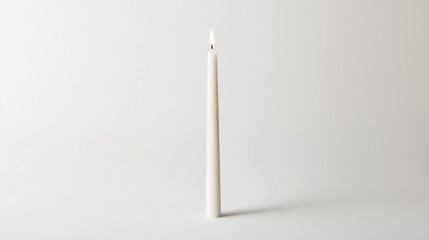 Lit white candle on plain backdrop