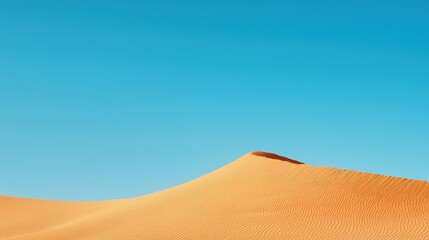 Person walking across a sandy dune under a clear blue sky in a desert landscape