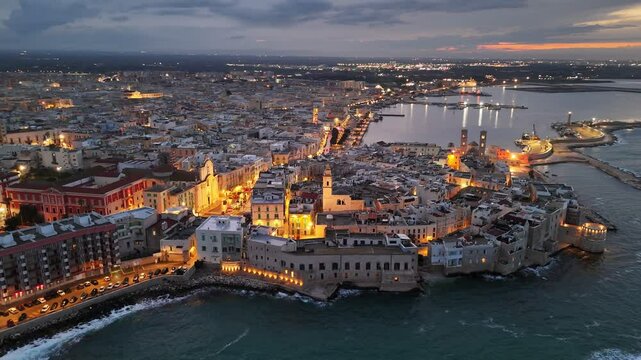 Aerial evening view of historic center of Molfetta, in the province of Bari, Puglia. Embankment and old town with city lights in Molfetta