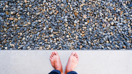 The top of the foot is seen stepping on a marble floor and in front of it there is a gravel base.