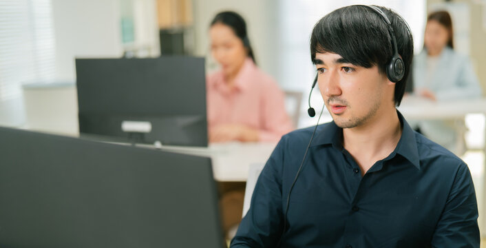 Attractive young businessman consultant and call center with headphones for customer service, support or online advice at office. Cheerful Telemarketing Representative Operator Providing CRM Support
