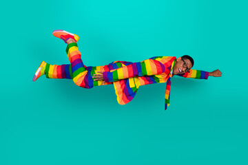 Stylish man in rainbow suit against teal background expressing individuality