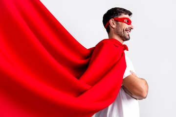 Confident Young Man in a Red Superhero Cape and Mask Posing Against a Neutral Background