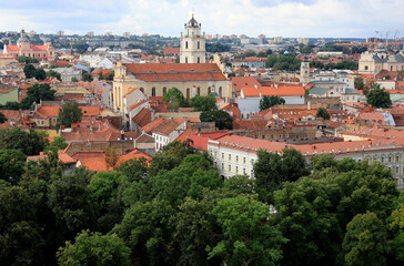 Fototapeta premium Panoramic view of the historical part of the city of Vilnius (Lithuania) with numerous churches and green trees in the foreground on the background of a stormy sky 