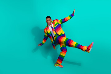 Colorful man in a rainbow-striped suit on a vibrant turquoise background expressing joy