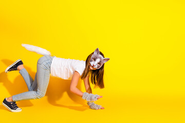Young girl dressed as a playful cat in a vibrant yellow background