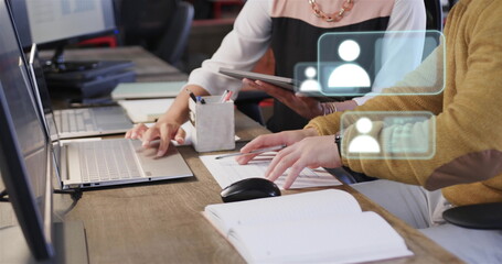 Image of social media icons over diverse colleagues using laptop in office