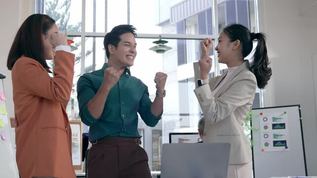 Young professionals rejoicing after completing successful project. Exuding collaborative spirit in contemporary, well lit office environment. Sharing workplace triumph with authentic team excitement