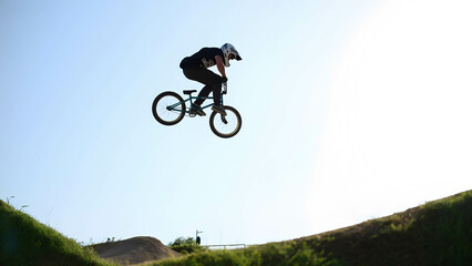 A BMX bike mid-air over a ramp, frozen in action against a bright sky