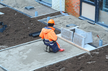 Construction worker laying a concrete slab in a new building site during daylight hours with a focus on precision and detail in the process