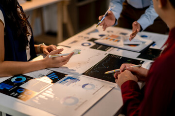 Three people are sitting at a table with papers and pens